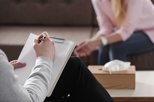 a man with a clipboard giving a counselling session to a female client